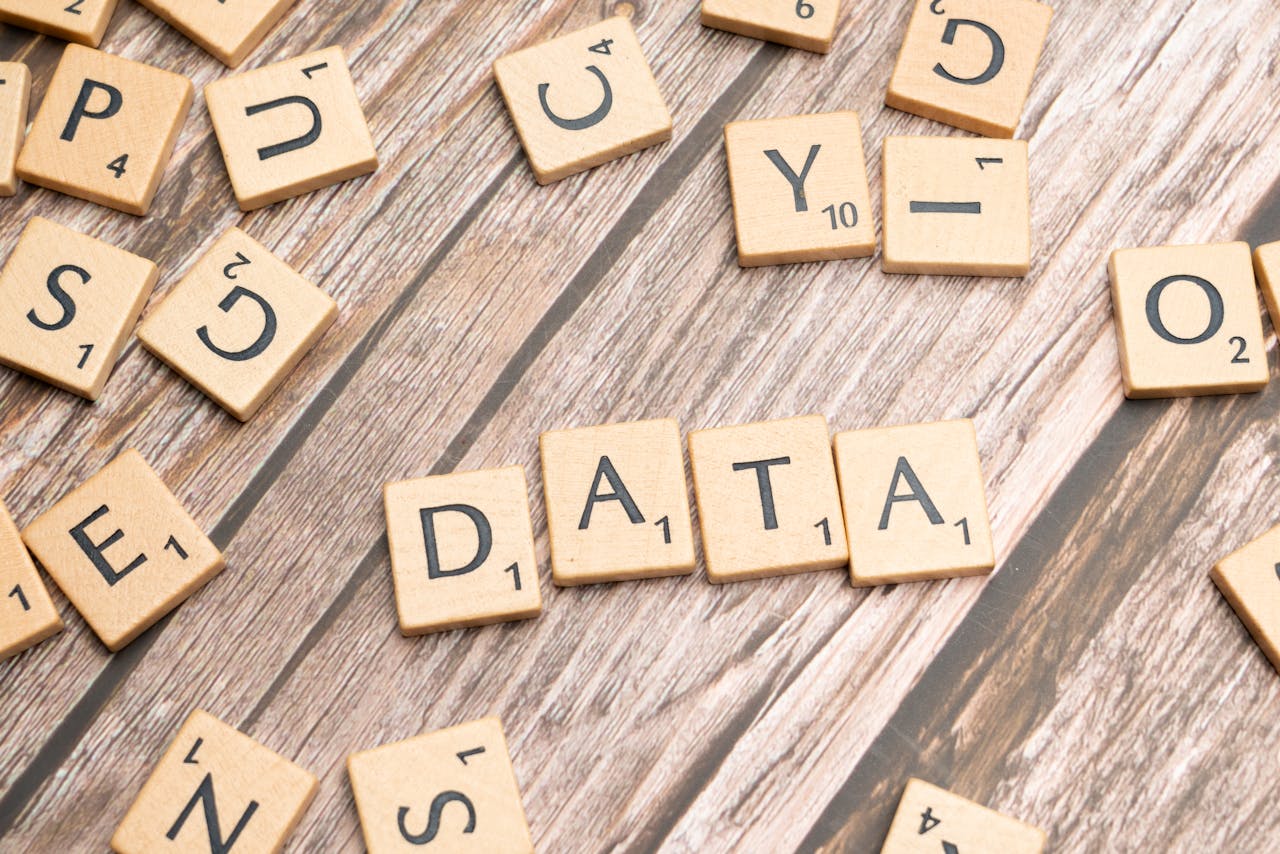 Wooden letter tiles spelling DATA on a wood textured surface, symbolizing data concepts.